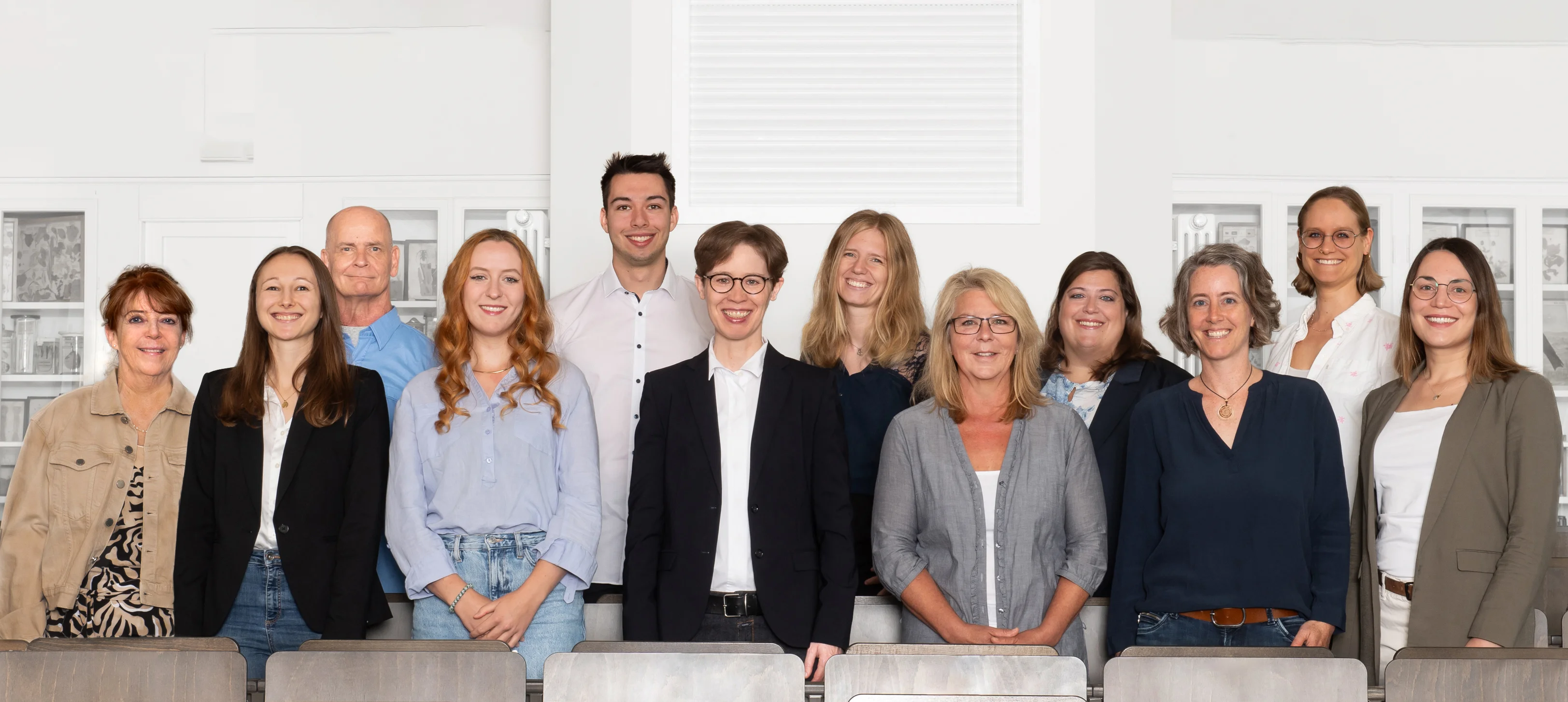 Eine Wissenschaftlerin und ein Wissenschaftler arbeiten hinter einer Glasfassade und mischen Chemikalien mit Großgeräten.